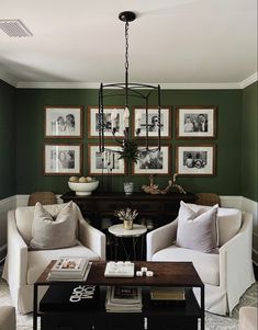 a living room with green walls and pictures on the wall above two couches, coffee table