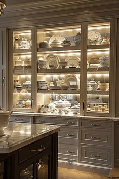 a kitchen with lots of white dishes on the shelves and lights in the cupboards