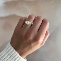 a woman's hand wearing a ring with a diamond on the middle and side