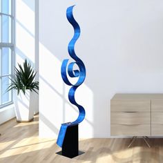 a tall blue sculpture in the middle of a room next to a dresser and window