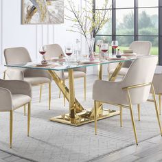 a glass table with gold legs and beige chairs