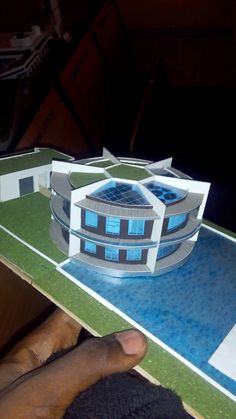 a paper model of a building on top of a blue and green flooring area