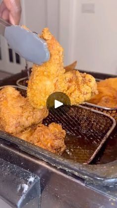 fried chicken being cooked in an air fryer with a spatula and tongs