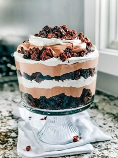 a layered cake with chocolate and cream toppings on a glass platter, ready to be eaten