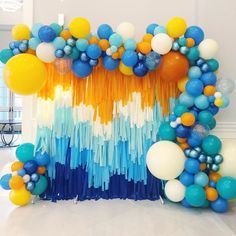 an arrangement of balloons and streamers in blue, orange, yellow and white colors