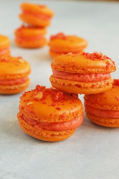 several orange donuts with sprinkles on them sitting on top of a table