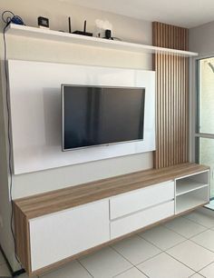 a flat screen tv sitting on top of a white entertainment center next to a sliding glass door