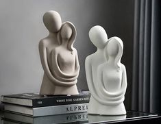 two white sculptures sitting on top of books