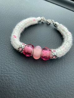 a pink beaded bracelet with two charms on it's end sitting on top of a car dashboard