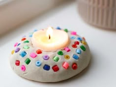 a candle that is sitting on top of a rock with sprinkles and dots