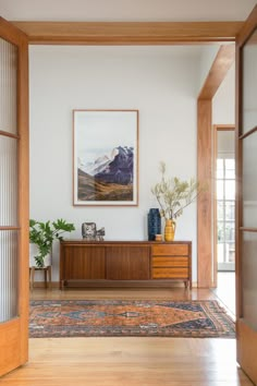 a living room with a large painting on the wall next to a wooden cabinet and door