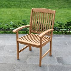 a wooden chair sitting on top of a stone floor next to a lush green field