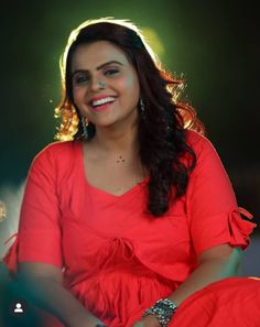 a smiling woman in a red dress sitting down