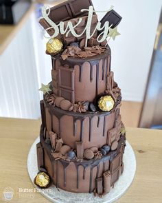 a three tiered cake with chocolate frosting and candies on the top layer