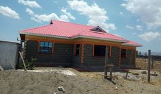 a small house with a red roof in the dirt