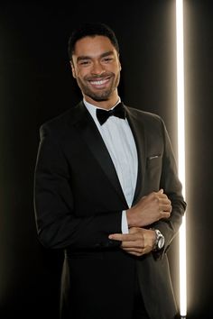 a man in a tuxedo is smiling and posing for the camera with his arms crossed