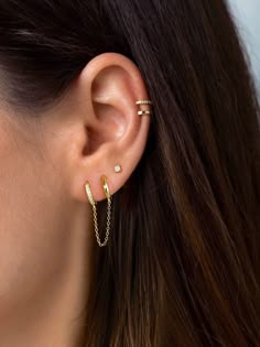 a woman wearing gold ear cuffs with two small bars attached to the back of her ear