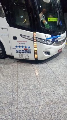 a white bus parked on top of a tiled floor