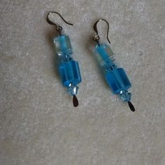 pair of blue glass beaded earrings on white carpeted floor with lightening effect