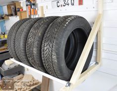 four tires are stacked up on a shelf in a garage, ready to be used