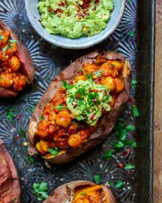 baked sweet potatoes with guacamole and salsa on top, ready to be eaten