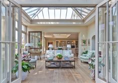 a living room filled with white furniture and lots of glass doors leading to an open floor plan