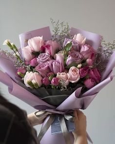 a woman holding a bouquet of pink roses