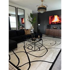 a living room filled with black furniture and a fire in the fireplace behind a large mirror