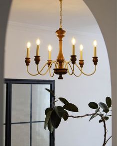 a chandelier hanging from the ceiling in a room with white walls and an arched doorway