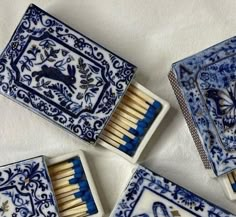 four matchboxes with blue and white designs are arranged in a square arrangement on a table