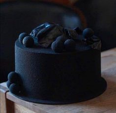 a black cake sitting on top of a wooden table