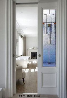 an open door leading to a living room with white furniture and stained glass windows in it