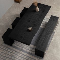 a wooden table sitting on top of a tiled floor next to a vase with flowers