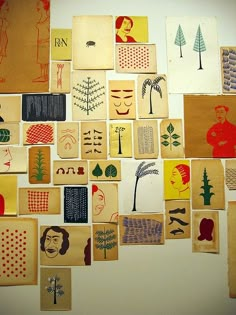 a wall covered in lots of different types of paper cut into squares with trees and people on them