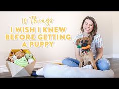 a woman is sitting on the floor with her dog and holding a toy in it's mouth