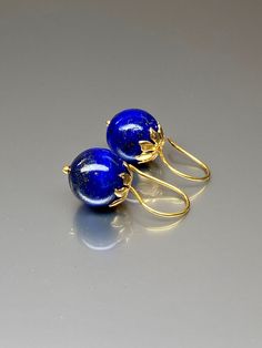 Beautiful vibrant and high-grade lapis lazuli globe earrings. The 12.5 mm lapis lazuli globes have a gorgeous deep vibrant royal blue color that shows celestial flecks of golden pyrite in the stone. The ultra-fine globes attached to a beautiful 14K gold-filled flower caps as they attached the vermeil on sterling ear wires. These are elegant and perfect earrings to go with any outfit. A pair of fine gemstone essentials. *Ball size (diameter): 12.5 mm *Metal: vermeil on sterling *Earrings drop len Blue Polished Drop Earrings, Blue Drop Earrings With Polished Finish, Elegant Lapis Lazuli Jewelry With Matching Earrings, Elegant Lapis Lazuli Gemstone Earrings, Blue Polished Finish Earrings For Gift, Pierced Lapis Lazuli Round Jewelry, Round Lapis Lazuli Gemstone Earrings, Blue Lapis Lazuli Earrings For Formal Occasions, Elegant Lapis Lazuli Earrings For Gift