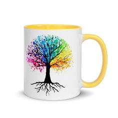 a coffee mug with a colorful tree painted on the front and bottom, in black rim