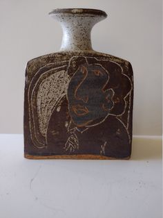 a brown and white vase sitting on top of a table