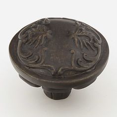 an antique style cabinet knob with floral design on the front and center, in bronze