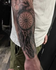 a man with a tattoo on his arm has a dream catcher in the middle of it