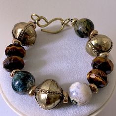 a bracelet with many different beads on it sitting on a white tablecloth covered surface