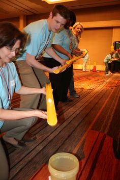 a group of people standing on top of a wooden floor holding yellow items in their hands