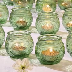 many green glass jars are lined up on a table