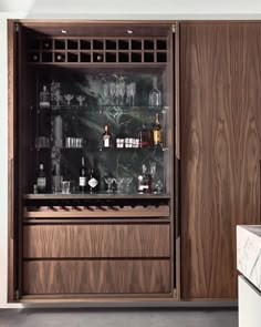 a wooden cabinet filled with lots of bottles and glasses next to a marble counter top