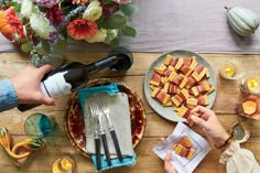 people are sitting at a table with food and wine