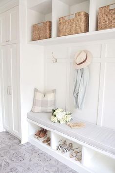 a white bench with shoes and flowers on it in front of some closets filled with baskets