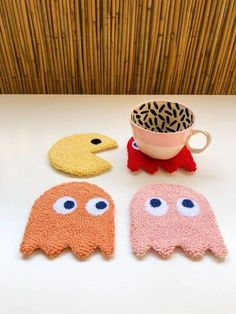 four bath mitts with different designs on them sitting on a table next to a cup and saucer