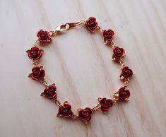 To symbolize the love that has blossomed in both your hearts, this exquisite bracelet is adorned with 12 intricately detailed roses. Each flower is masterfully crafted to capture the lush beauty of a rose in glorious full bloom. The effect is trulybreathtaking! Material: Gold Plated Copper Length: 19cm Adjustable Rose Red Flower Jewelry, Adjustable Rose Red Bracelet As Gift, Adjustable Rose Red Bracelet For Gift, Adjustable Rose Red Bracelet Perfect For Gifts, Adjustable Rose Red Bracelets As Gift, Rose Gold Bracelet With Rose Design For Gift, Red Flower Bracelets For Valentine's Day, Elegant Rose Color Bracelet For Gift, Metal Rose Design Jewelry For Valentine's Day