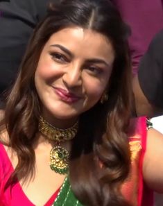 a woman in a pink and green sari smiles at the camera with her hand on her hip