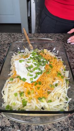 a glass dish filled with shredded cheese and green onions